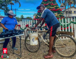 Belize: man on bike with woman selling shoes, April 2022